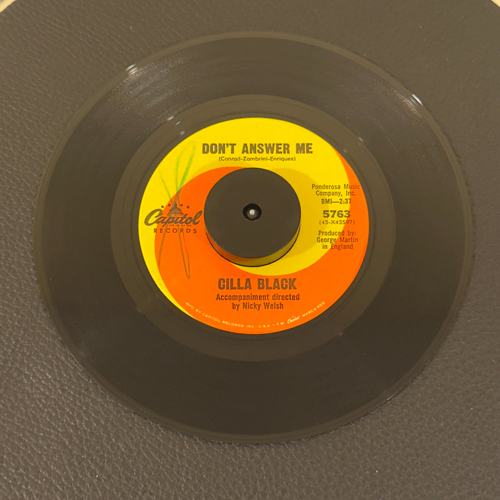 7" vinyl record by Cilla Black featuring "Don't Answer Me/The Right One Is Left", released on Capitol Records (5763), in VG+ (Very Good Plus) condition, classic analog collectable for turntable playback. Includes original Capitol Records sleeve.  Writing on Side A of label.