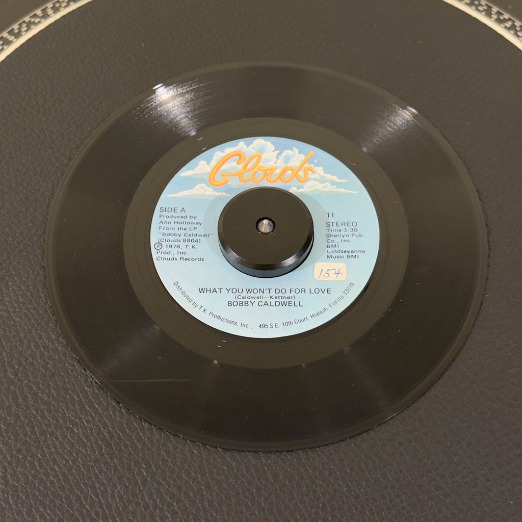 7" vinyl record by Bobby Caldwell featuring "What You Won't Do For Love/Love Won't Wait", released on Disco (11), in VG (Very Good) condition, classic analog collectable for turntable playback. Undisputed banger sampled by various artists, inlcuding 2Pac & Aailiyah. Sticker on Side A.