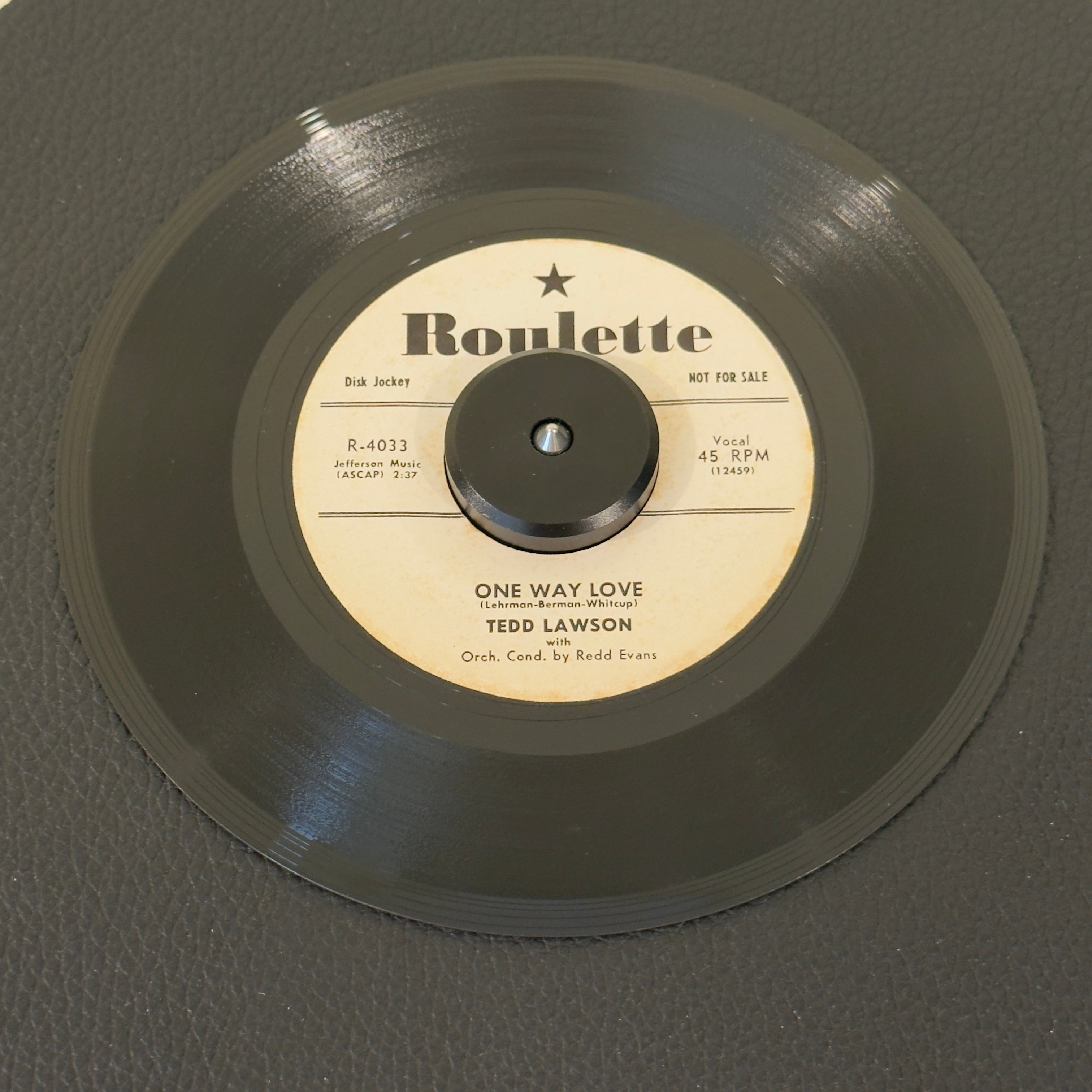 7" vinyl record by Ted Lawson featuring "One Way Love/Wasteland", released on Roulette (R-4033), in VG+ (Very Good Plus) condition, classic analog collectable for turntable playback. 1957 US white-label promotional pressing released during the foundational first year of legendary New York imprint Roulette Records.  Includes original sleeve.