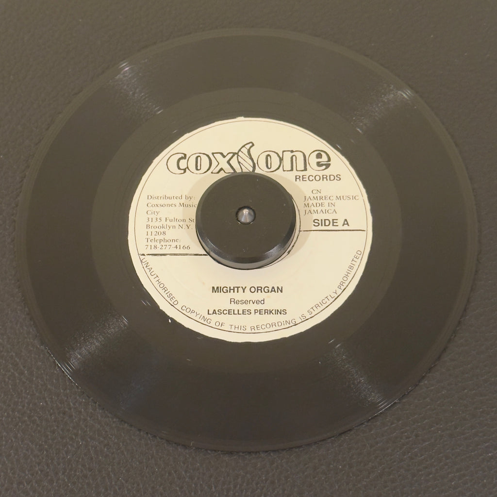 7" vinyl record by Lascelles Perkins featuring "Mighty Organ/Westbound No. 9 (Flaming Ember)", released on Coxsone Records (), in VG (Very Good) condition, classic analog collectable for turntable playback. Incredible piece of Jamaican vinyl manufacturing history: a rare, highly sought-after Coxsone Records hybrid split single! Westbound No 9 by The Flaming Embers on the B side.
