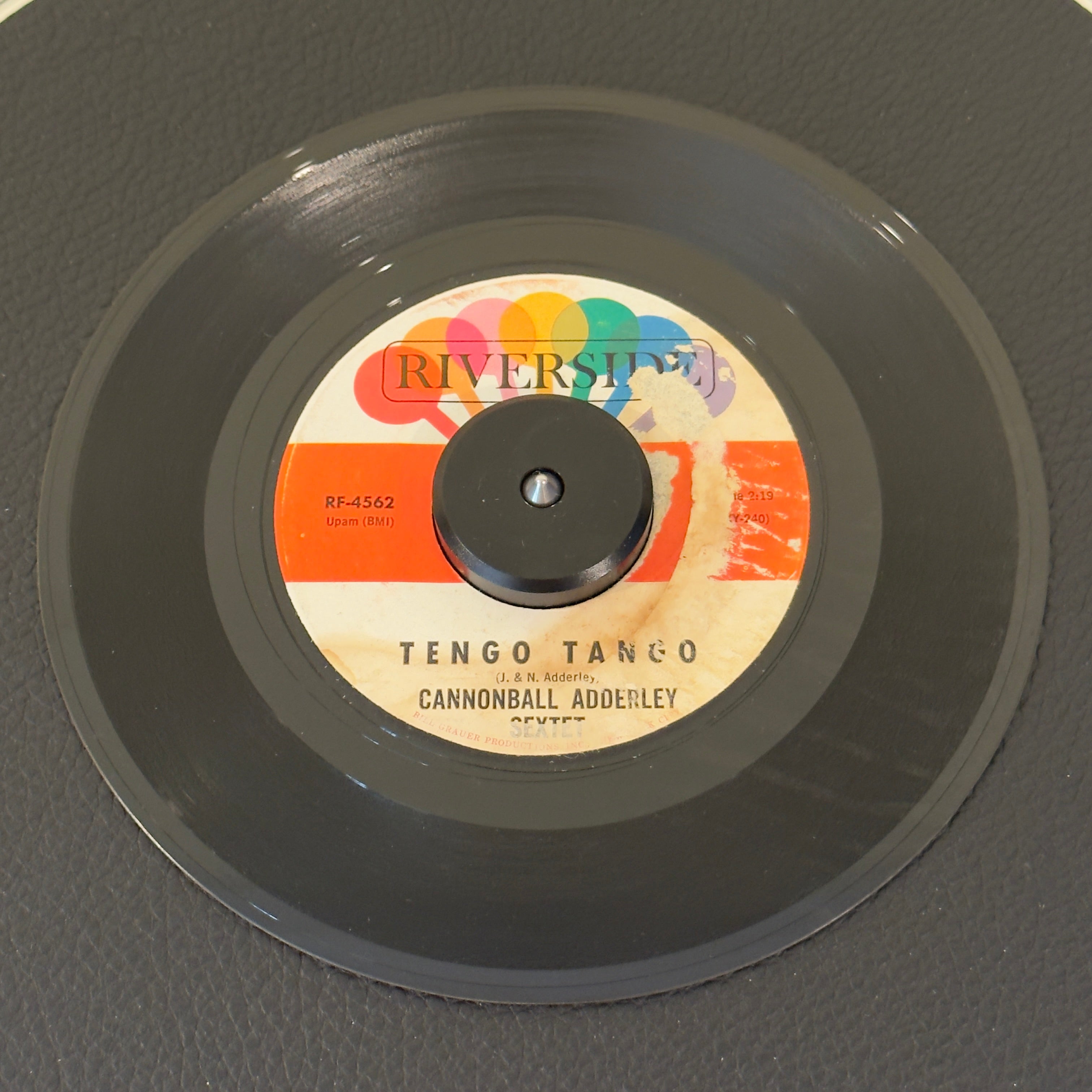 7" vinyl record by Cannonball Adderley Sextet featuring "Tengo Tango/Brother John", released on Riverside Records (RF-4562), in VG (Very Good) condition, classic analog collectable for turntable playback. Highly notable among collectors for being the exact rare studio single contextually highlighted within the liner notes of the legendary Nippon Soul live album.  Damage on label.