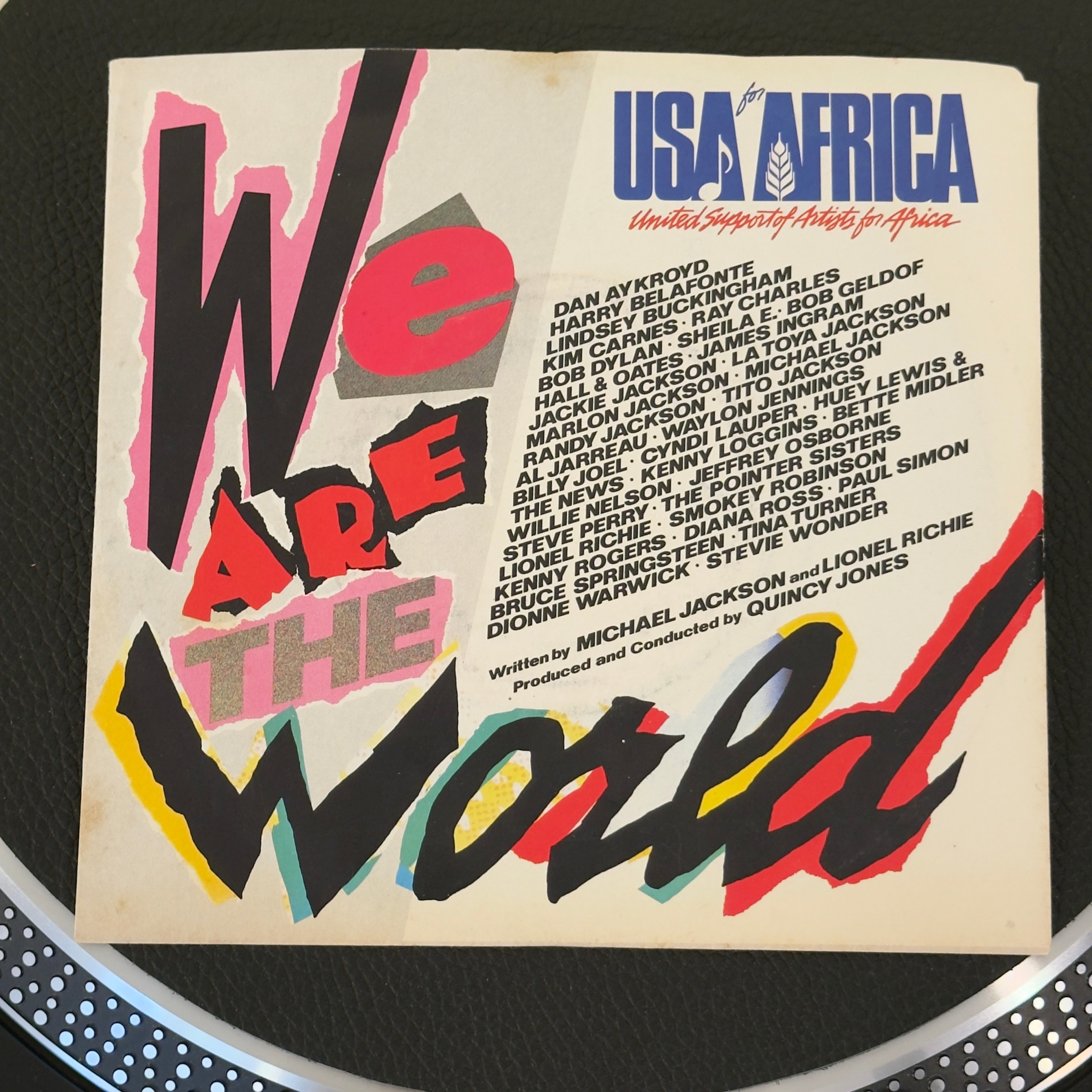 7" vinyl record by USA for Africa featuring "We Are The World/Grace (Quincy Jones)", released on Columbia (US7-04839), in NM (Near Mint) condition, classic analog collectable for turntable playback. Written by Michael Jackson and Lionel Richie, produced by Quincy Jones, this monumental track brought together over 40 of the biggest music icons of the 20th century to combat famine in Africa.