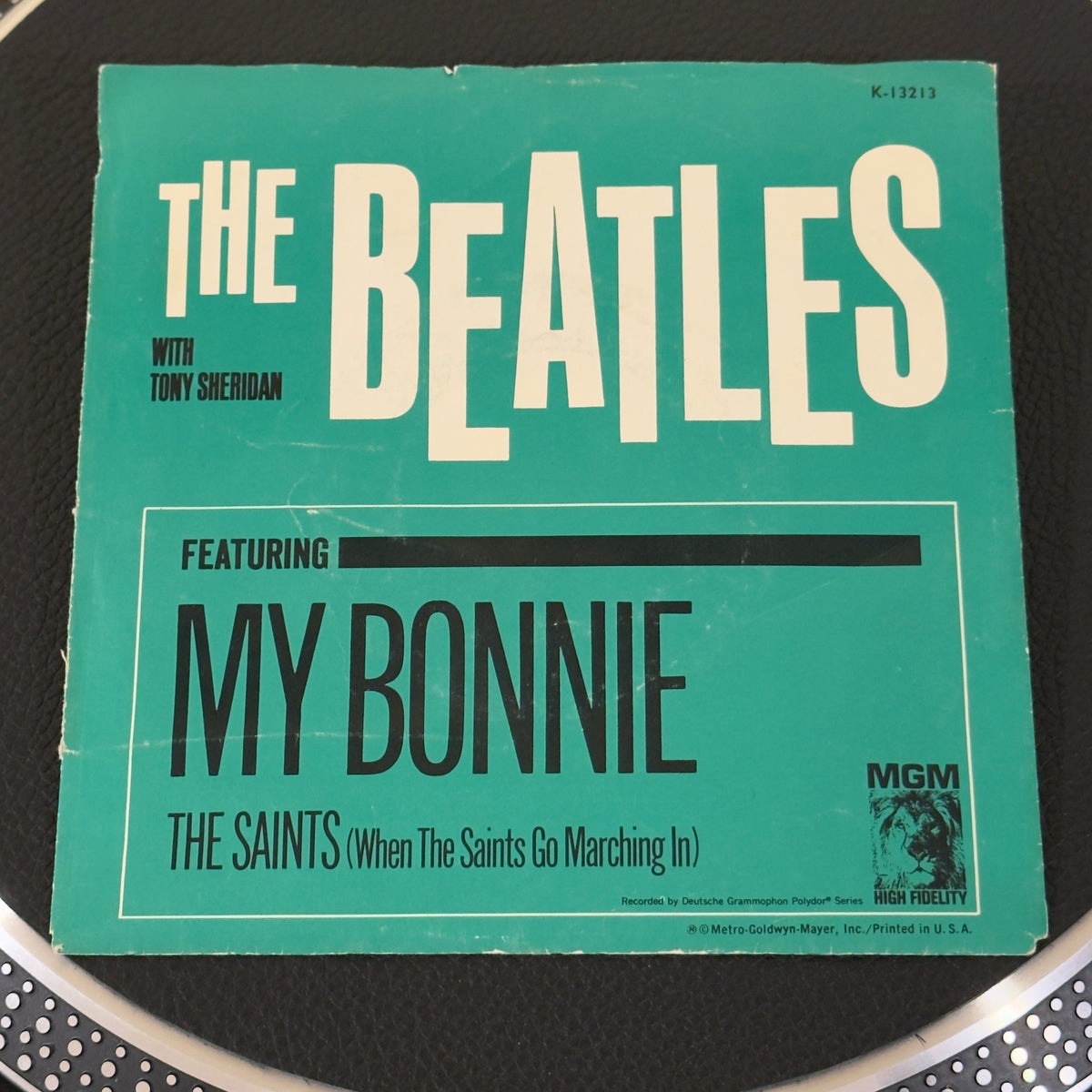 7" vinyl record by Beatles, The W/ Tony Sheridan featuring "My Bonnie (My Bonnie Lies Over The Ocean)/The Saints (When The Saints Go Marching In)", released on MGM Records (K-13213), in VG (Very Good) condition, classic analog collectable for turntable playback. MGM reissued these historic 1961 recordings in 1964 just as the band took America by storm.  Pic Sleeve.