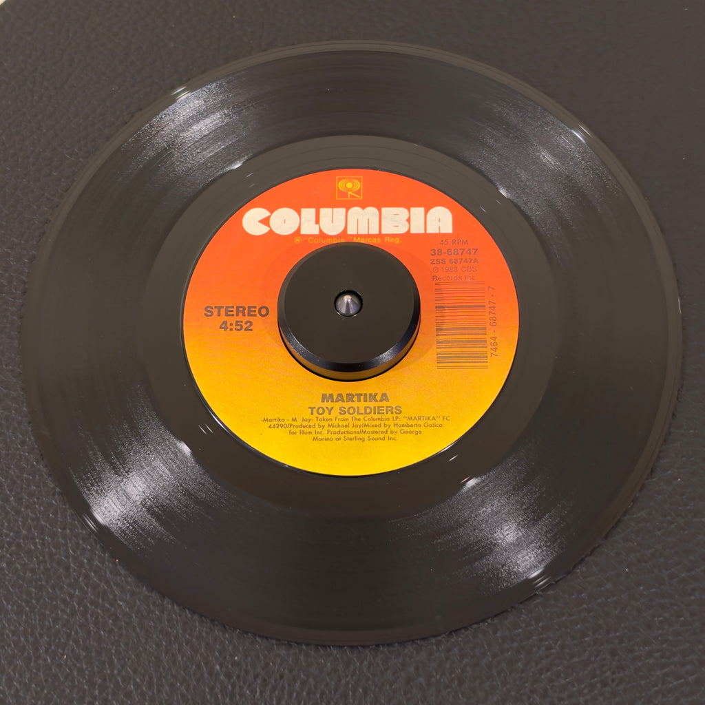 7" vinyl record by Martika featuring "Toy Soldiers/Exchange Of Hearts", released on Columbia (38-68747), in VG+ (Very Good Plus) condition, classic analog collectable for turntable playback. Beautiful copy of late-80s pop perfection #1 Billboard smash hit. This single features the haunting backing vocals of Stacy Ferguson (later known as Fergie of the Black Eyed Peas).
