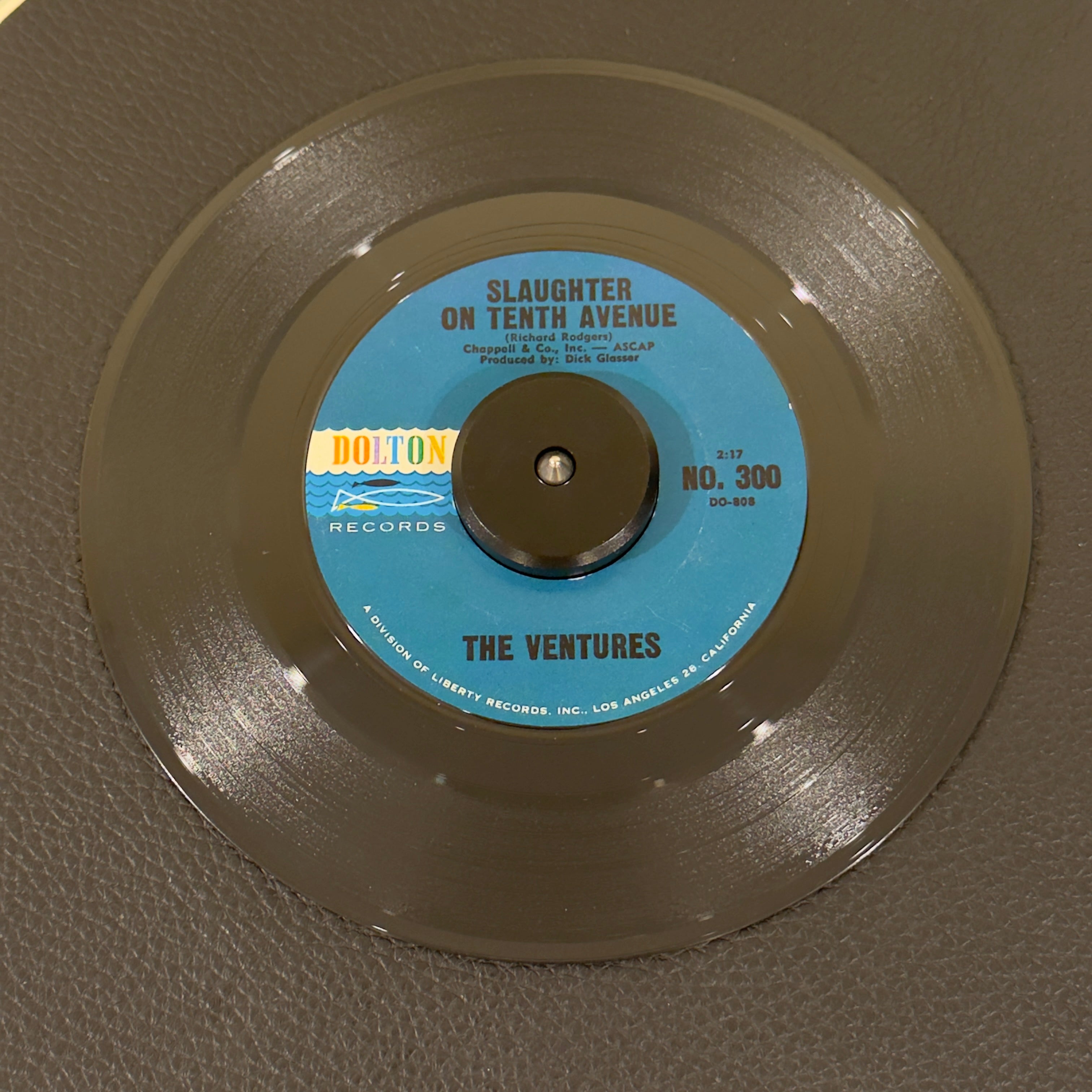 7" vinyl record by Ventures, The featuring "Slaughter On Tenth Avenue/Rap City", released on Dolton Records (NO.300), in NM (Near Mint) condition, classic analog collectable for turntable playback. Amazing copy including the original Dolton sleeve! Perfect for your Ventures collection!  Ring on label (SideB).